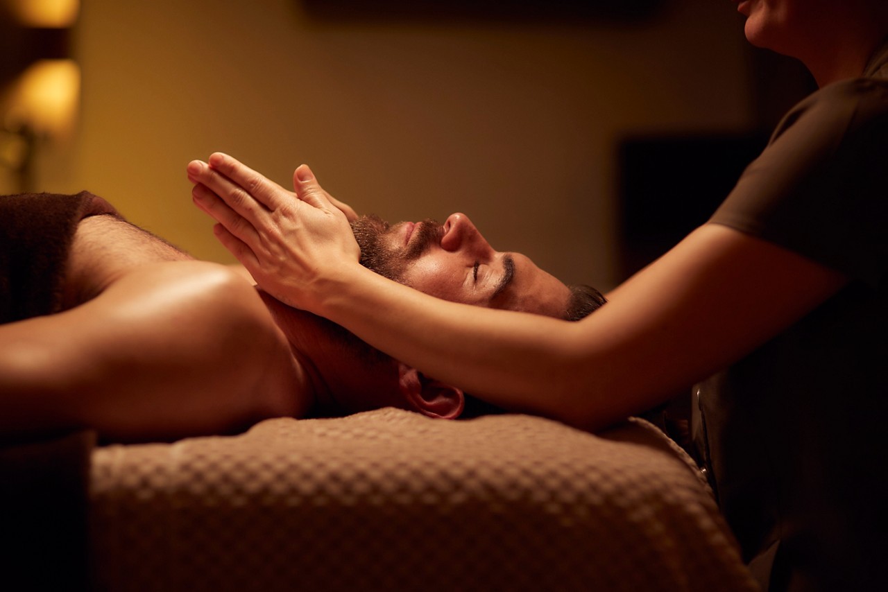 Spa therapist giving a man a relaxing facial treatment.
